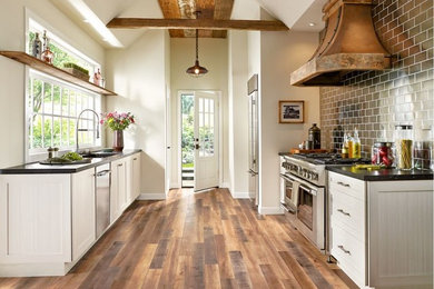 Example of a mid-sized classic galley laminate floor enclosed kitchen design in Kansas City with an undermount sink, shaker cabinets, white cabinets, soapstone countertops, stainless steel appliances and no island
