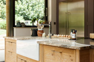 Modern kitchen with a belfast sink, marble worktops, stainless steel appliances, limestone flooring and multiple islands.