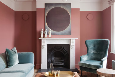 This is an example of a small contemporary enclosed living room in London with pink walls, light hardwood floors, a standard fireplace and beige floor.