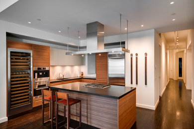 Inspiration for a contemporary l-shaped dark wood floor open concept kitchen remodel in New York with an undermount sink, flat-panel cabinets, medium tone wood cabinets, white backsplash, stainless steel appliances, an island and black countertops