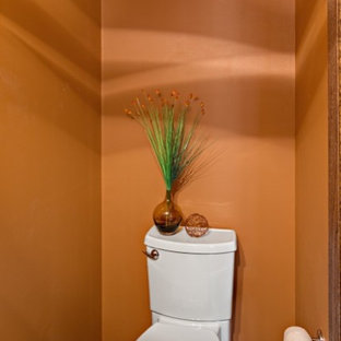 Foto di un piccolo bagno di servizio moderno con lavabo integrato, ante lisce, ante in legno scuro, WC a due pezzi, pareti arancioni, pavimento in gres porcellanato e piastrelle grigie