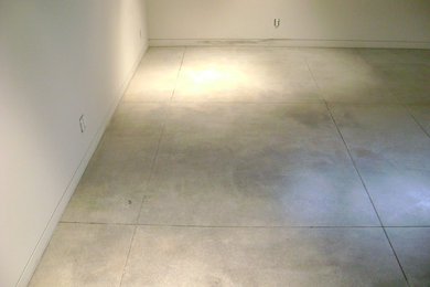 Diseño de sótano en el subsuelo moderno grande sin chimenea con paredes blancas y suelo de cemento