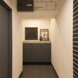 他の地域のインダストリアルスタイルのおしゃれな玄関ホール (白い壁、磁器タイルの床、黒い床) の写真