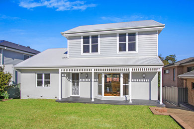 Photo of a large beach style two-storey multi-coloured house exterior in Wollongong with mixed siding, a gable roof and a metal roof.