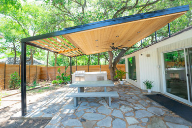 Mid-sized minimalist stone porch idea in Austin with a pergola