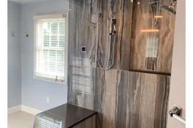 Large trendy master multicolored tile porcelain tile and beige floor corner shower photo in DC Metro with glass-front cabinets, brown cabinets, a two-piece toilet, blue walls, a vessel sink, granite countertops, a hinged shower door and brown countertops