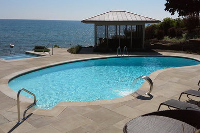 Design ideas for a mid-sized transitional backyard kidney-shaped pool in Chicago with a hot tub and concrete pavers.