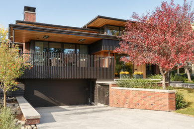 This is an example of a mid-sized midcentury one-storey house exterior in Calgary with wood siding and a black roof.