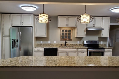 Inspiration for a mid-sized timeless galley light wood floor and brown floor enclosed kitchen remodel in Jacksonville with a double-bowl sink, raised-panel cabinets, white cabinets, granite countertops, stainless steel appliances and brown countertops