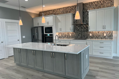Open concept kitchen - large transitional single-wall laminate floor and gray floor open concept kitchen idea in Other with a double-bowl sink, shaker cabinets, white cabinets, quartzite countertops, multicolored backsplash, glass tile backsplash, an island and white countertops