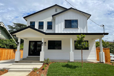 Example of a large country white two-story stucco and board and batten exterior home design in Sacramento with a shingle roof and a black roof
