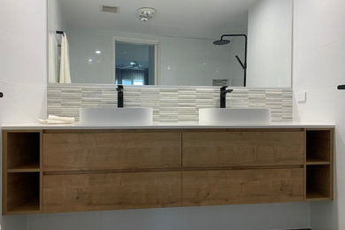 Mid-sized contemporary bathroom in Sunshine Coast with light wood cabinets, a one-piece toilet, white tile, ceramic tile, white walls, cement tiles, a vessel sink, solid surface benchtops, grey floor, white benchtops, a niche, a double vanity and a floating vanity.
