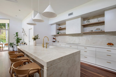 This is an example of a large contemporary l-shaped kitchen pantry in Sydney with an undermount sink, shaker cabinets, beige cabinets, quartzite benchtops, multi-coloured splashback, stone slab splashback, black appliances, medium hardwood floors, with island, brown floor, multi-coloured benchtop and vaulted.