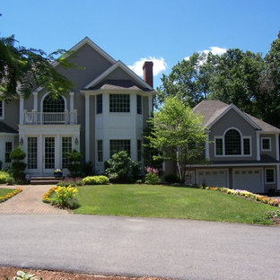 Удачное сочетание для дизайна помещения: большой, двухэтажный фасад дома серого цвета в классическом стиле с облицовкой из дерева и полувальмовой крышей - самое интересное для вас