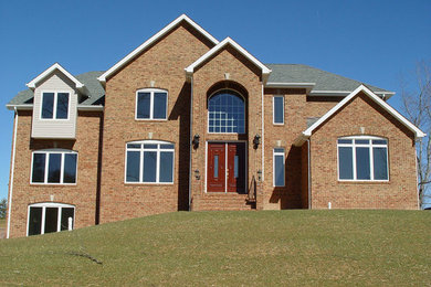 Inspiration for a huge timeless beige three-story brick exterior home remodel in Other with a hip roof