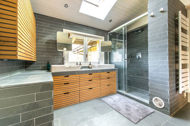 Idée de décoration pour une salle de bain principale nordique en bois clair de taille moyenne avec une baignoire encastrée, WC suspendus, un carrelage gris, du carrelage en ardoise, un mur gris, un sol en ardoise, un lavabo posé, un sol gris et une cabine de douche à porte coulissante.