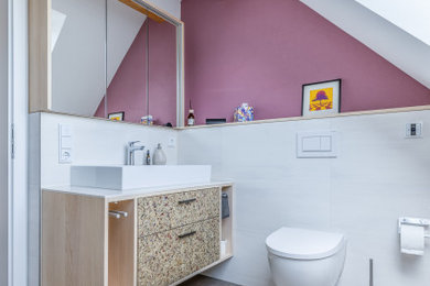 Kleines Modernes Badezimmer mit hellen Holzschränken, Wandtoilette, weißen Fliesen, Aufsatzwaschbecken, grauem Boden, weißer Waschtischplatte, Einzelwaschbecken, schwebendem Waschtisch und freigelegten Dachbalken in Frankfurt am Main