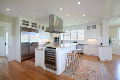 Example of a mid-sized classic u-shaped medium tone wood floor and brown floor open concept kitchen design in Providence with shaker cabinets, white cabinets, granite countertops, white backsplash, porcelain backsplash, stainless steel appliances and an island