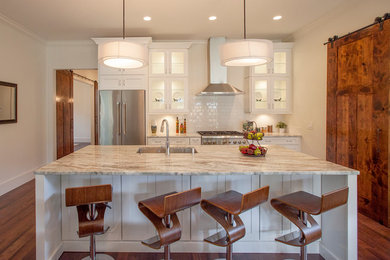 Inspiration for a transitional galley kitchen in Orlando with an undermount sink, glass-front cabinets, white cabinets, white splashback, subway tile splashback, stainless steel appliances, medium hardwood floors, with island and granite benchtops.