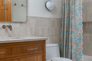 Inspiration for a transitional gray tile white floor and single-sink bathroom remodel in Minneapolis with shaker cabinets, medium tone wood cabinets, white walls, an undermount sink, gray countertops, a niche and a freestanding vanity