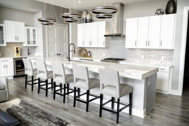 Inspiration for a contemporary eat-in kitchen in Indianapolis with shaker cabinets, white cabinets, white splashback, subway tile splashback, stainless steel appliances, laminate floors, with island and grey floor.