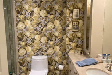 Inspiration for a mid-sized tropical master beige tile and porcelain tile porcelain tile, beige floor, single-sink and wallpaper bathroom remodel in Toronto with recessed-panel cabinets, a one-piece toilet, a hinged shower door, beige countertops and a built-in vanity