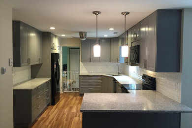 Large trendy u-shaped vinyl floor eat-in kitchen photo in DC Metro with an undermount sink, raised-panel cabinets, gray cabinets, quartzite countertops, white backsplash, subway tile backsplash, black appliances and a peninsula