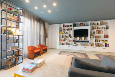 Modelo de biblioteca en casa tipo loft actual grande con paredes azules, suelo de cemento, televisor colgado en la pared y suelo gris