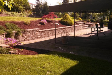 Example of a mid-sized classic backyard concrete paver patio design in Other with an awning