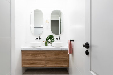 This is an example of a mid-sized beach style master bathroom in Sydney with shaker cabinets, white tile, porcelain tile, porcelain floors, a vessel sink, marble benchtops, grey floor, white benchtops, a double vanity, a floating vanity and medium wood cabinets.