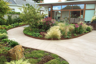 Mid-sized beach style backyard partial sun formal garden in Dublin with concrete pavers.