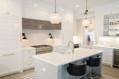 Example of a mid-sized minimalist u-shaped light wood floor, brown floor and coffered ceiling eat-in kitchen design in Boston with a farmhouse sink, flat-panel cabinets, gray cabinets, quartzite countertops, white backsplash, quartz backsplash, stainless steel appliances, an island and white countertops