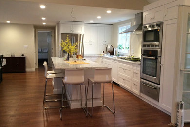 Mid-sized transitional l-shaped medium tone wood floor and brown floor eat-in kitchen photo in Boston with an undermount sink, shaker cabinets, white cabinets, marble countertops, multicolored backsplash, glass tile backsplash, stainless steel appliances and an island