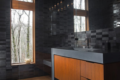 Mid-sized contemporary bathroom in Atlanta with a trough sink, black tile, ceramic tile, black walls, porcelain floors, flat-panel cabinets and black floor.