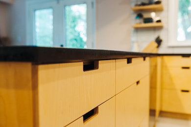 Inspiration for a mid-sized scandinavian u-shaped ceramic tile and gray floor eat-in kitchen remodel in Other with an undermount sink, flat-panel cabinets, light wood cabinets, soapstone countertops, white backsplash, porcelain backsplash, stainless steel appliances, a peninsula and black countertops