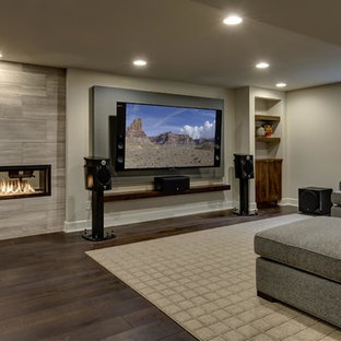 Expansive contemporary look-out basement in Denver with grey walls, dark hardwood flooring, a ribbon fireplace, a tiled fireplace surround and brown floors.
