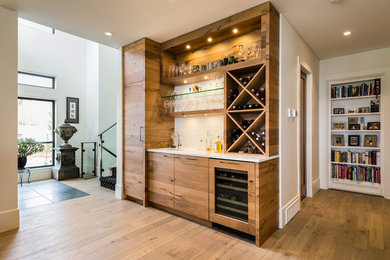 Wet bar - large contemporary single-wall wet bar idea in Vancouver with an undermount sink, flat-panel cabinets, medium tone wood cabinets, quartz countertops, white backsplash and white countertops