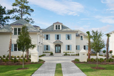 Example of a beach style white two-story brick house exterior design with a hip roof and a gray roof