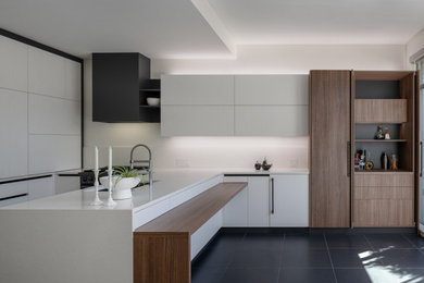 Example of a huge minimalist l-shaped porcelain tile and black floor eat-in kitchen design in Vancouver with an undermount sink, flat-panel cabinets, white cabinets, quartz countertops, white backsplash, quartz backsplash, black appliances, a peninsula and white countertops