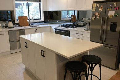 Photo of a mid-sized contemporary l-shaped eat-in kitchen in Sydney with an undermount sink, shaker cabinets, white cabinets, quartz benchtops, metallic splashback, mirror splashback, stainless steel appliances, porcelain floors and with island.