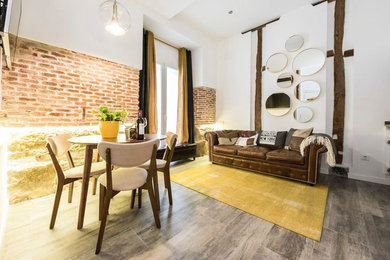 Design ideas for an industrial open concept living room in Madrid with white walls and brown floor.