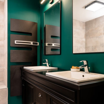 Salle de bains aux notes naturelles, mobilier & accessoires noirs sur fond vert