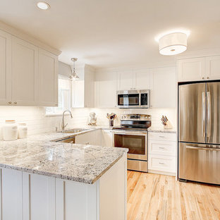 Cette photo montre une petite arrière-cuisine tendance en U avec un évier encastré, un placard à porte shaker, des portes de placard blanches, une crédence blanche, une crédence en carrelage métro, un électroménager en acier inoxydable, un sol en bois clair, une péninsule et un plan de travail en granite.