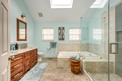 Mid-sized modern master bathroom in Philadelphia with beaded inset cabinets, brown cabinets, blue tile, engineered quartz benchtops, beige benchtops, a drop-in tub, a corner shower, a two-piece toilet, glass tile, blue walls, porcelain floors, an undermount sink, beige floor and a hinged shower door.