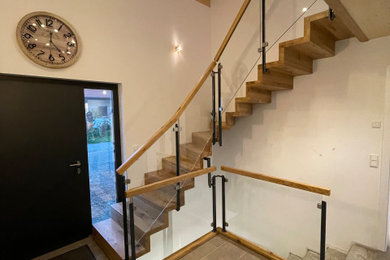 他の地域にあるコンテンポラリースタイルのおしゃれなかね折れ階段 (木の蹴込み板、ガラスフェンス、レンガ壁) の写真