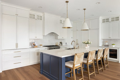Example of a large transitional l-shaped laminate floor and brown floor eat-in kitchen design in Orange County with an undermount sink, shaker cabinets, blue cabinets, quartzite countertops, white backsplash, porcelain backsplash, paneled appliances, an island and white countertops