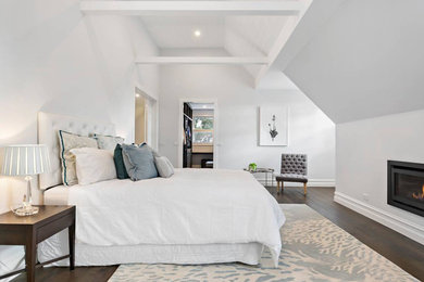 Design ideas for a large traditional master bedroom in Melbourne with white walls, dark hardwood floors, a standard fireplace, a plaster fireplace surround and brown floor.