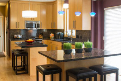 Example of a minimalist u-shaped open concept kitchen design in Minneapolis with an undermount sink, flat-panel cabinets, black backsplash, stone slab backsplash, stainless steel appliances and an island