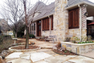 Mid-sized tuscan brown two-story stone house exterior photo in Dallas with a hip roof and a mixed material roof