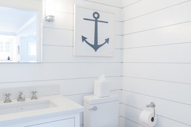 Small beach style 3/4 bathroom in Boston with shaker cabinets, white cabinets, a one-piece toilet, white tile, white walls, medium hardwood floors, an undermount sink, engineered quartz benchtops, white benchtops and brown floor.